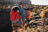 Outdoor scene with a person carrying a dog in a Ruffwear Hitch Hiker Dog Backpack Carrier while hiking.